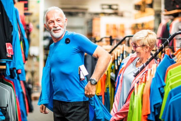 istock Elderly man trying on a soft shell hiking jacket while his partner is watching in an outdoor equipment store 1224569791