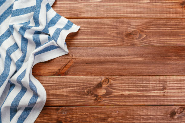 istock Top view on a dark wooden table with a linen kitchen towel or textile napkin. a tablecloth on a countertop made of old wood. Copy space for text. 1224569929