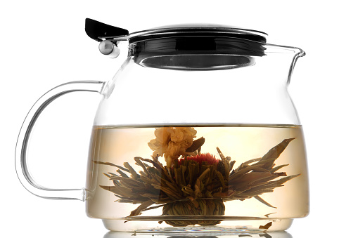 Yellow herbal tea in glass teapot and cup with leaves and berries. Close-up   freshly brewed hot tea.