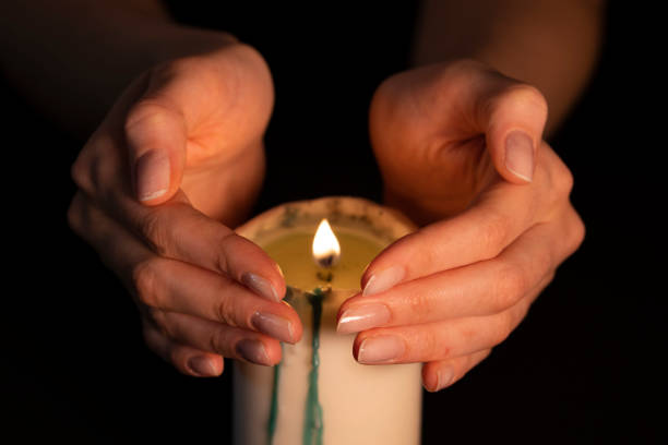 istock Women's hands above the burning candle close-up. Magic fire, the witch predicts. Isolate on a black background, a static shot 1224570966