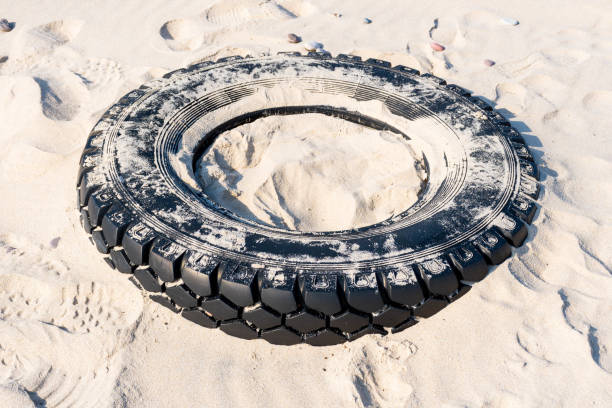 Old car tire on the beach. Plastic pollution and ecological problems concept.