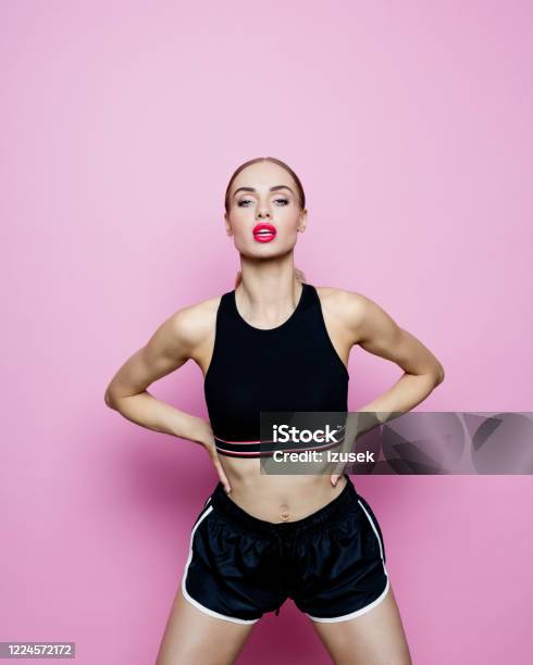 Studio Portrait Of Confident Woman In Sports Clothing Against Pink Background Stock Photo - Download Image Now