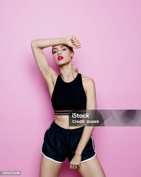 Studio Portrait Of Slim Woman In Sports Clothing Against Pink Background Stock Photo - Download Image Now