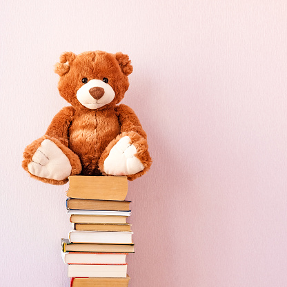 Soft stuffed toy Teddy bear sits on a stack of books . Education concept, back to school, reading speed