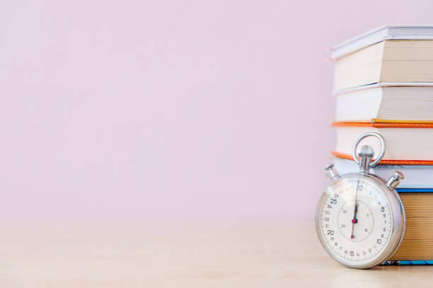 istock Stack of books and stopwatch on simple backdrop. Copy space for your text. 1224574824