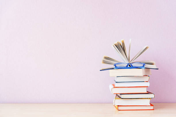 istock Many books and blue glasses on simple lilac backdrop. Copy space for your text. 1224574827