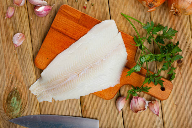 Fresh halibut fillet with seasonings Fresh halibut fillet on wooden surface with seasonings prepared for cooking turbot stock pictures, royalty-free photos & images