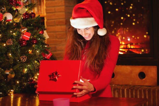 istock On Christmas days a beautiful woman opens her gift under the Christmas tree, and as she opens the gift she lights up like magic. 1224579021