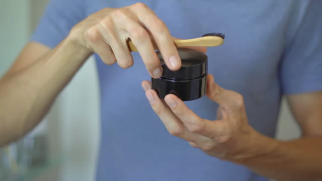 A young man brushes his teeth with a brush made of bamboo wood using charcoal for teeth whitening. Zero waste concept. Biodegradable products concept