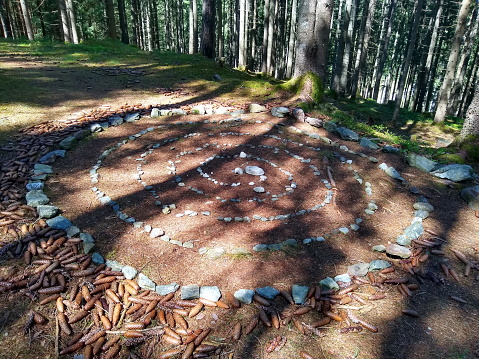 celtic stone spiral with pine cones in sunlight at forest clearing