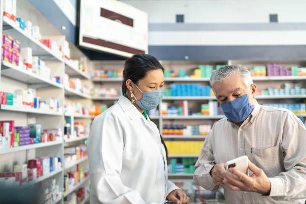 Female pharmacist helping a senior customer Female pharmacist helping a senior customer chemist stock pictures, royalty-free photos & images