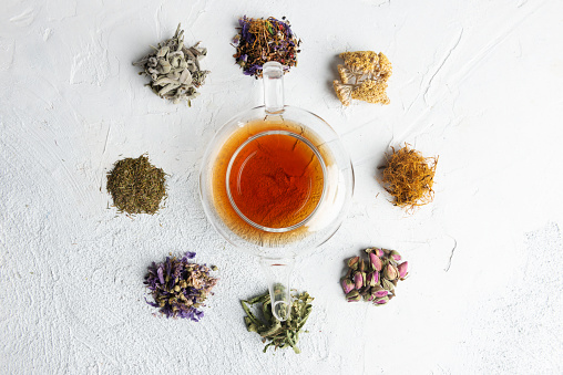 Directly above view of a tea pot with herbal tea. Surrounded by a variety of herbal teas  like Chamomile tea, Sage tea, Linden tea, Fennel tea, Melissa tea, Rose tea,  Rosemary Tea and Corn silk tea.