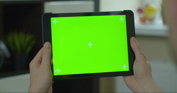 istock Man using tablet with green screen for internet surfing online. Close up chromakey screen. 1224596331