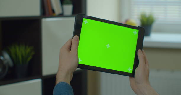 istock Young man holding TabletPC in hands, playing mobile game. TabletPC with green screen in chroma key. 1224596344