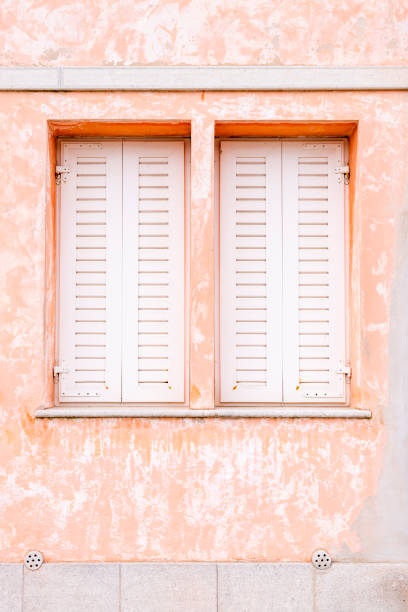 istock An old house wall and two windows with white wood shutters 1224596408