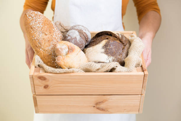 istock Baker wearing apron, carrying wooden box with loafs 1224604457