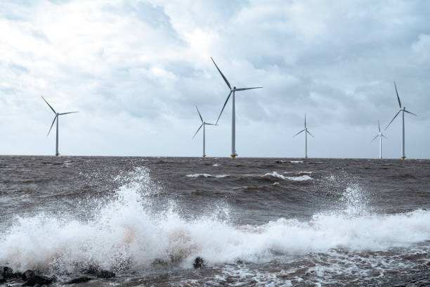 Wind turbines in an offshore wind park during a storm with big waves hitting the shore Wind turbines in an offshore wind park during a storm with big waves hitting the shore. flevoland photos stock pictures, royalty-free photos & images