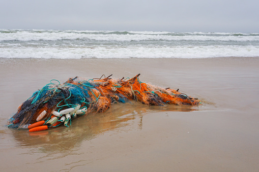 Fishing nets on a sand after sea storm. Garbage in the nature. Environmental pollution. Ecological problem.