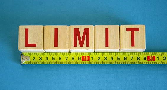 'Limit' word on cubes arranged behind the ruler on beautiful blue background. Concept.