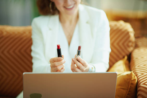 mujer sonriente con portátil y dos labiales vlogging - red lipstick fotografías e imágenes de stock