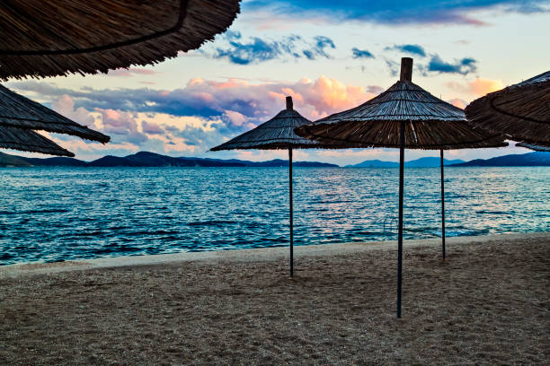 Empty beach with reed beach umbrellas, nobody on the beach. Beautiful evening sky, sunset. Beach with no travelers and tourists. Cancellations due to coronavirus covid-19. Quarantine.
