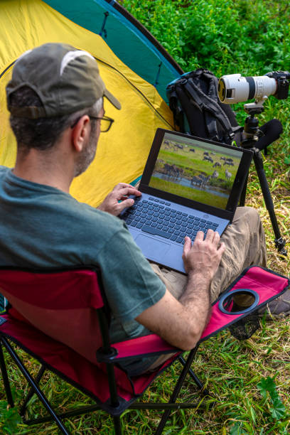 istock Photographer working on laptop in a tent camp. 1224612759