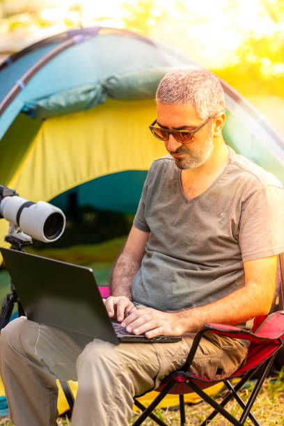 istock Photographer working on laptop in a tent camp. 1224613030
