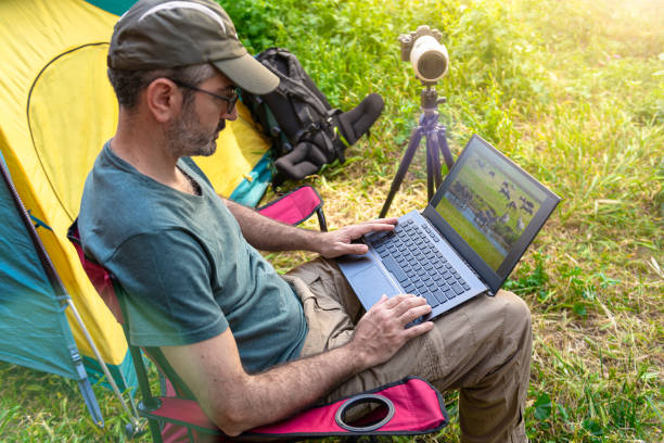 istock Photographer working on laptop in a tent camp. 1224613665
