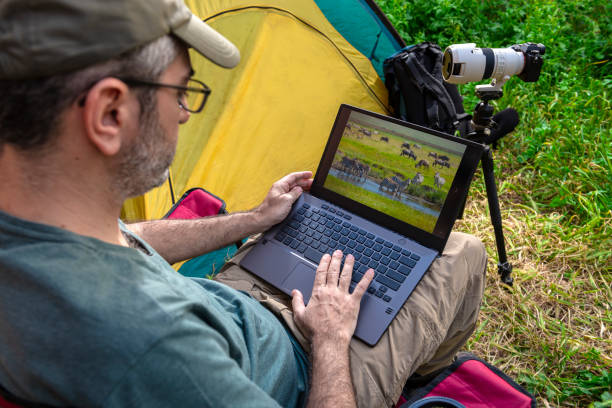 istock Photographer working on laptop in a tent camp. 1224614692