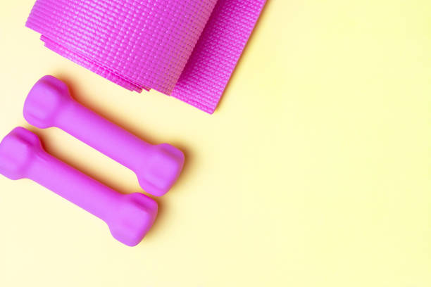 istock Pink sports mat and dumbbells on yellow background, copy space 1224616929