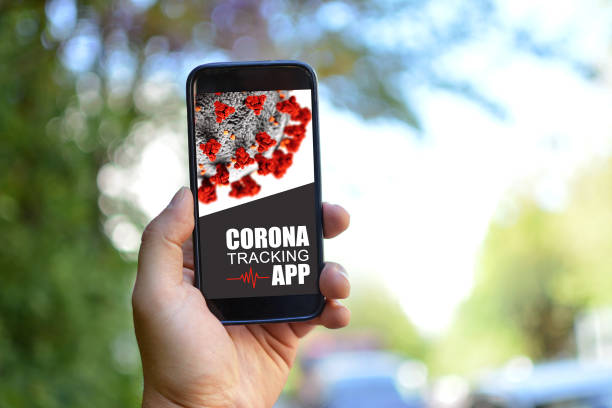 istock Tracking App concept for Corona virus with hand holding mobile phone with application design on screen in front of blurry outdoor background 1224617192