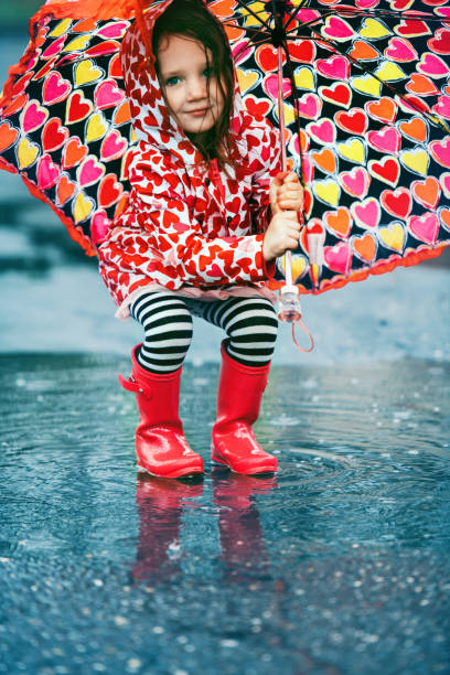 istock 4 years little girl jumping in puddle 1224619376
