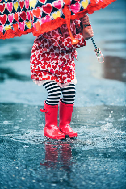 istock 4 years little girl jumping in puddle 1224619378