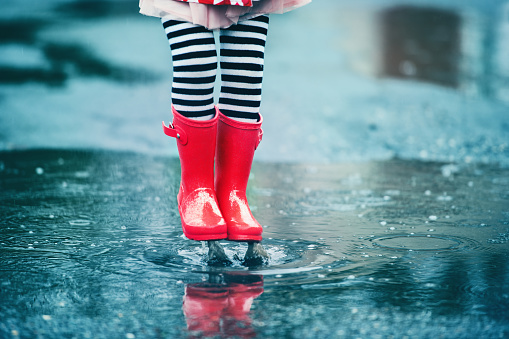 4 years little girl jumping in puddle