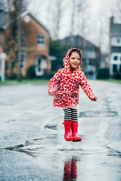 istock 4 years little girl jumping in puddle 1224619434