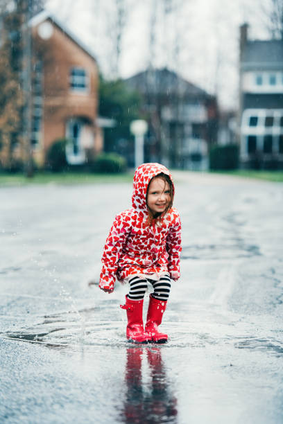istock 4 years little girl jumping in puddle 1224619435