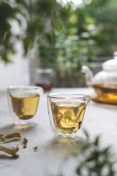 istock Summer linden flowers tea with splashes on white light table with bokeh 1224619640
