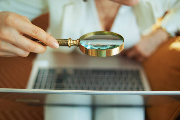 istock Closeup on woman with laptop using magnifying glass 1224619822