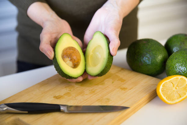 istock Woman showing avocado halves over kitchen table 1224627257