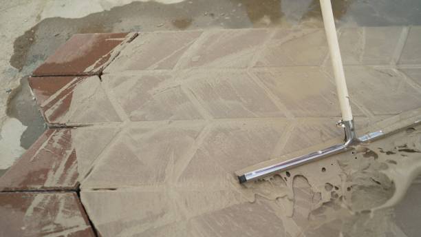 istock Worker hand with bucket pouring cement for tiles installation making on floor. Road tile with mortar. Filling glue on the road tile. 1224628451