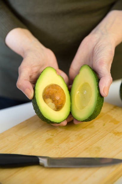 istock Woman holding avocado halves over kitchen table 1224630560