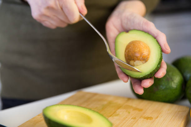 istock Woman removing seed from avocado half with spoon over 1224632152
