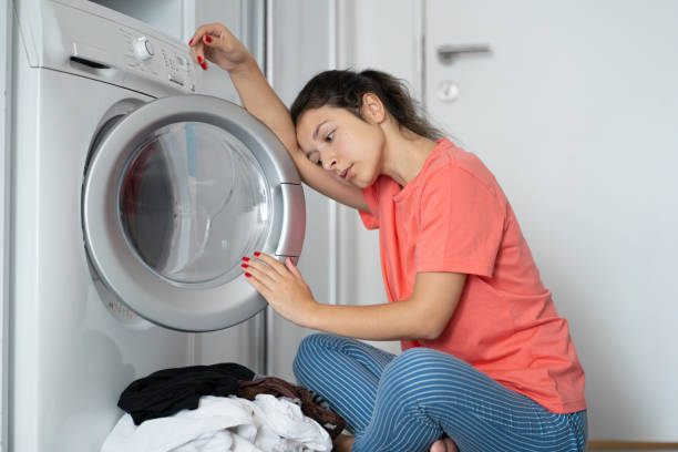 istock A girl loads dirty laundry into a washing machine while sitting on the floor in an apartment. Laundry day, housework. 1224636310
