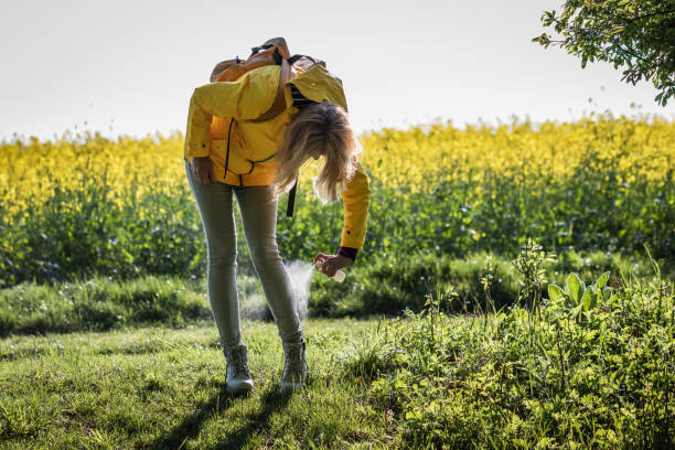 Woman using insect repellant against tick in nature