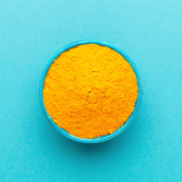 istock Top view turmeric powder in blue bowl at orange background. 1224637509