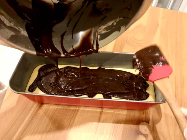 istock Hands Working with Spatula for Marble Cake Preparation Recipe and Pouring Chocolate Sauce. 1224638780