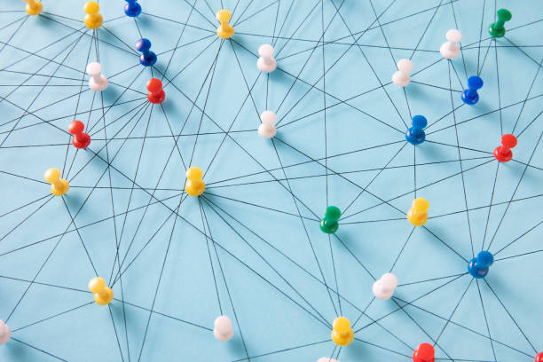 Small Network of Pins An arrangement of colorful pins linked together with string on a pale blue background suggesting a network of connections. map pins string stock pictures, royalty-free photos & images