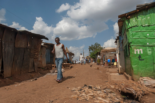 Nairobi, Kenya - February 29th, 2012: Unidentified man walks down a dirty street in Kibera, Nairobi, Kenya. Kibera is the biggest slum in Africa with high unemployment and crime.