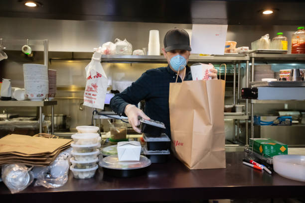 istock Masked and Gloved Restaurant Worker Packaging Food for Delivery During Covid-19 Outbreak 1224640653