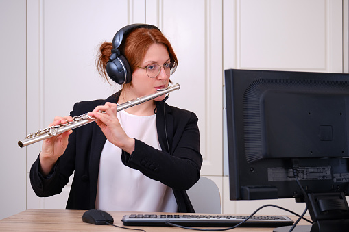 A music teacher conducts a lesson on playing a musical instrument over the Internet. Flute lessons online and online music training during quarantine for the coronavirus pandemic